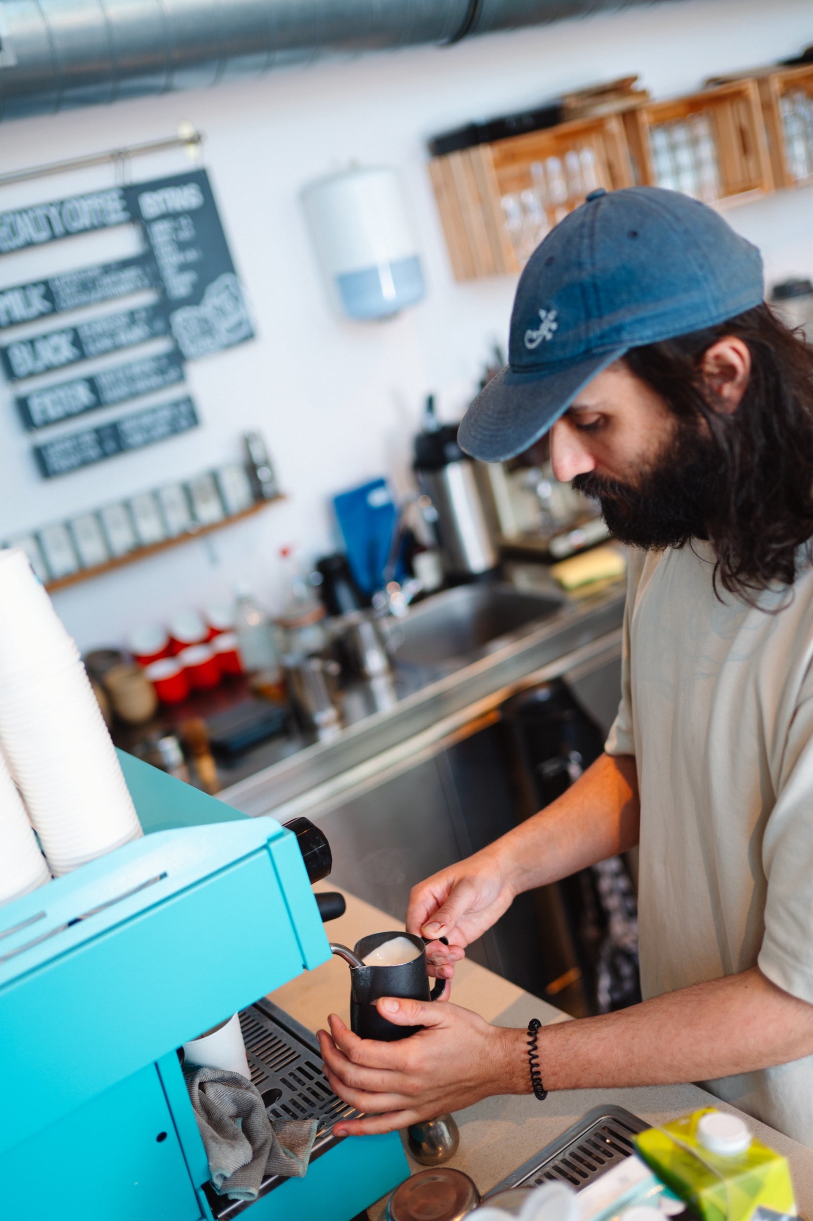 Person making coffee in a kitchen setting with a teal espresso machine.