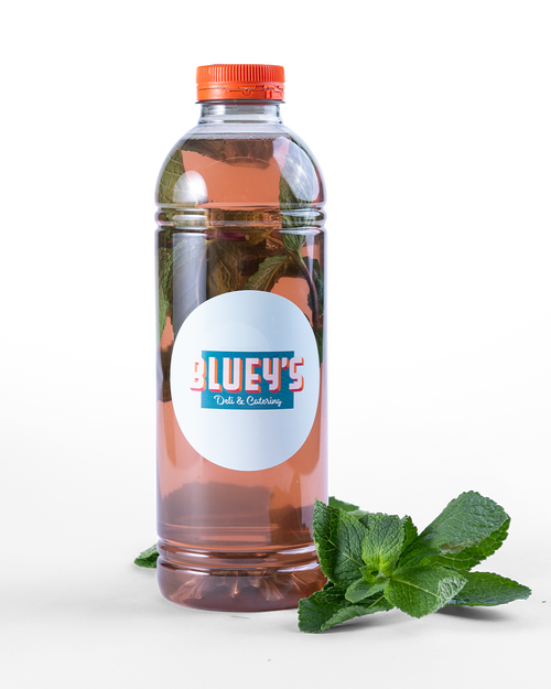 Bottle of 'Bluey's' lemonade with a orange cap and label, accompanied by mint leaves. To order with BLUEYS catering in Amsterdam.
