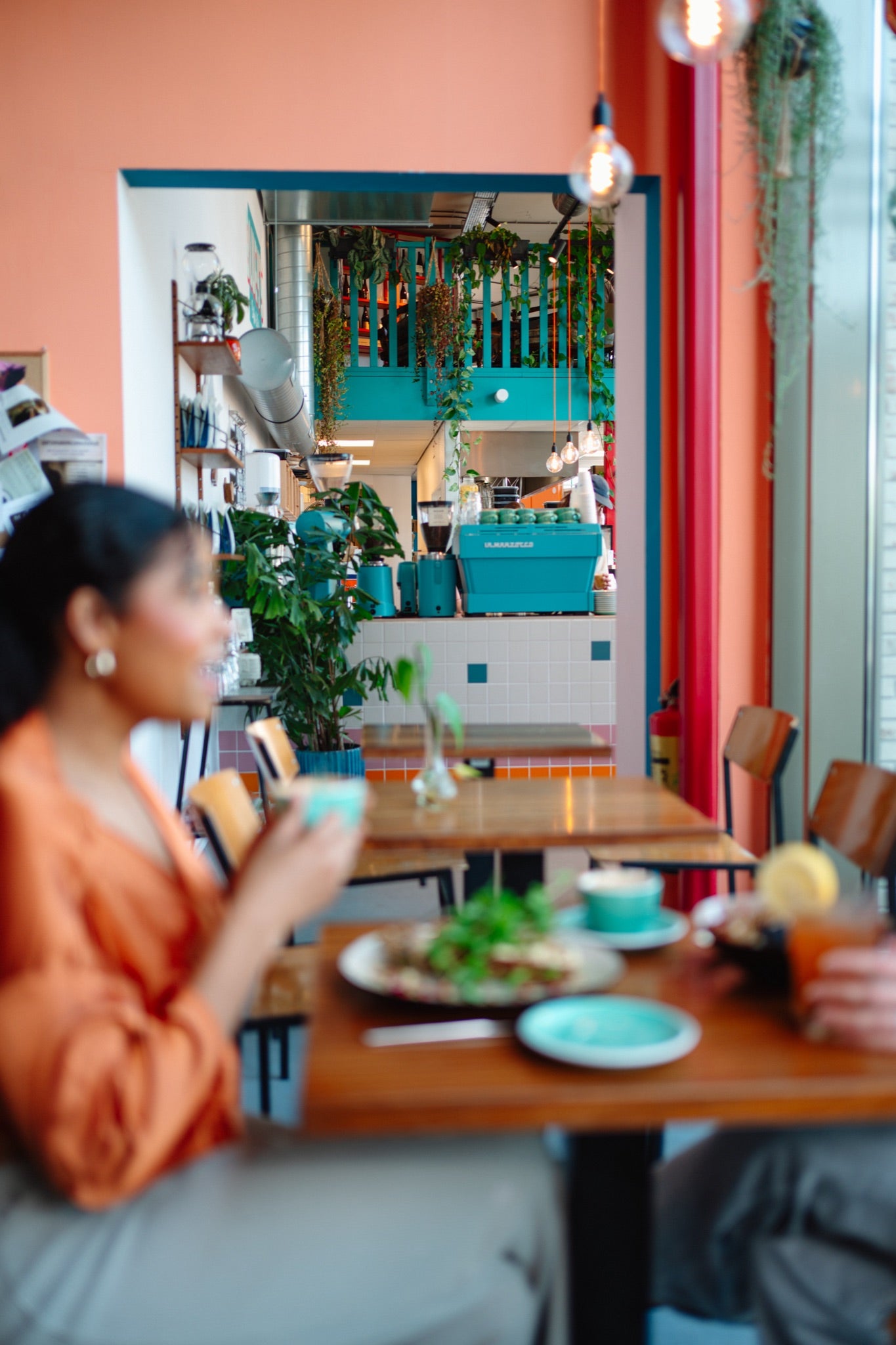 Person sitting at a table in a colourful and bright all-day-brunch cafe in amsterdam